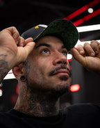 Model wearing a black cap with graphic underside in a modern indoor setting