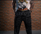 Model wearing black graphic print pants with white swirl patterns, hands in pockets