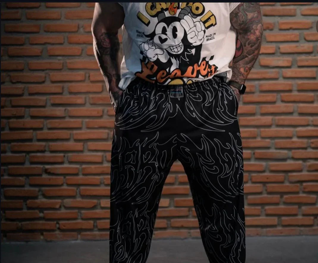Model wearing black graphic print pants with white swirl patterns, hands in pockets