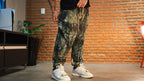 Model wearing camo print jogger pants with white sneakers in indoor setting