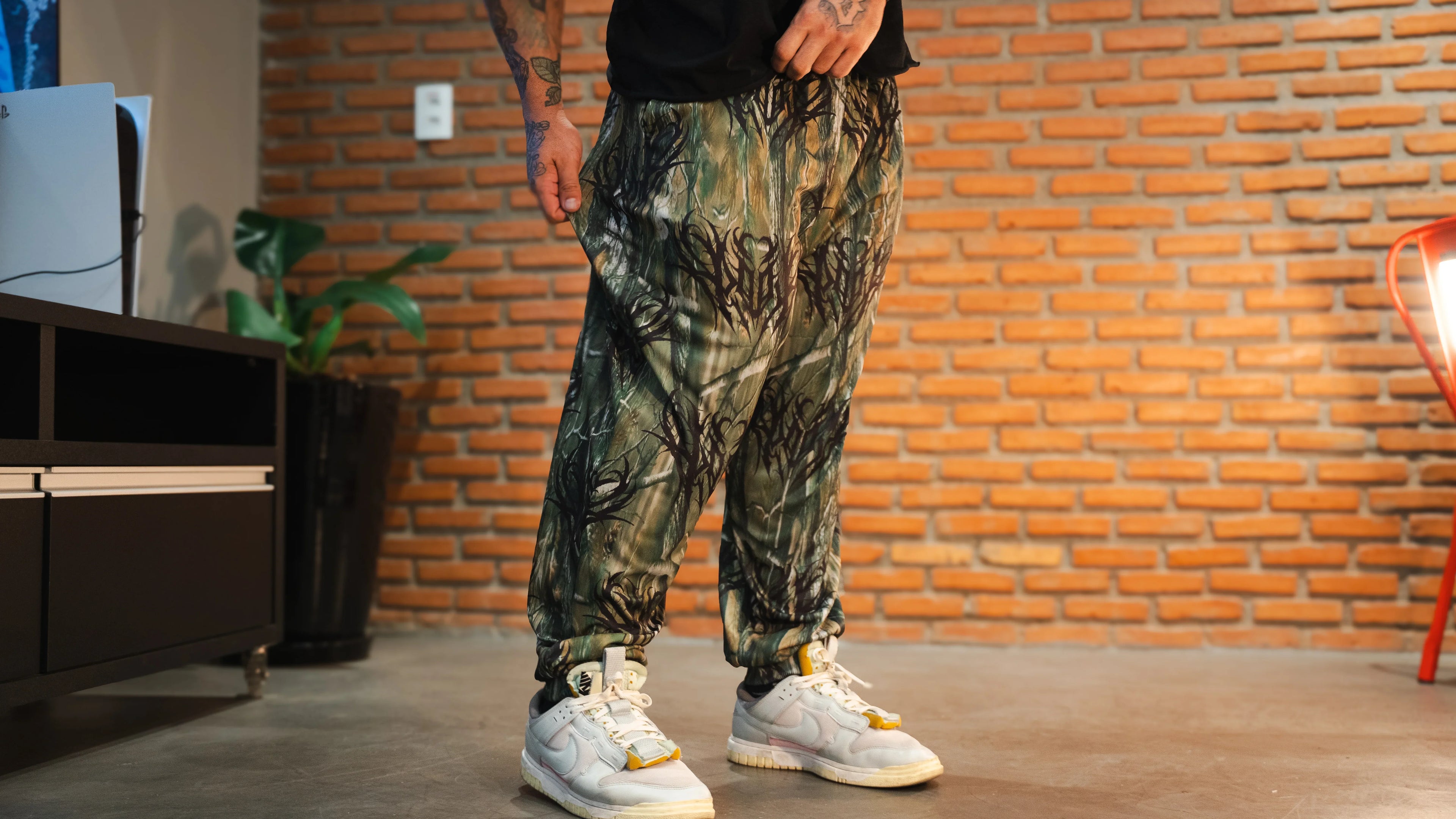Model wearing camo print jogger pants with white sneakers in indoor setting