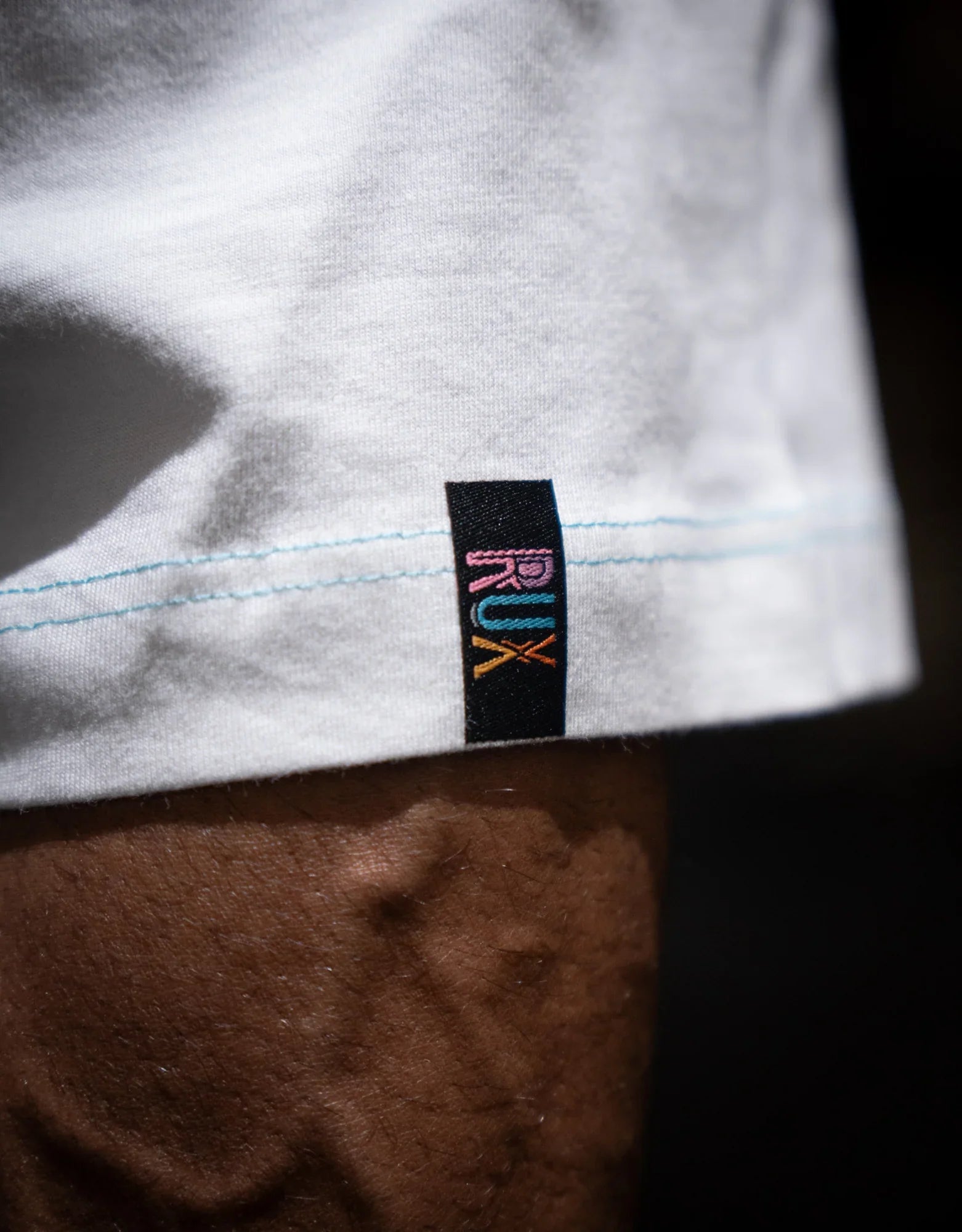 Model wearing white pants with visible hem stitching and a black fabric tag detail