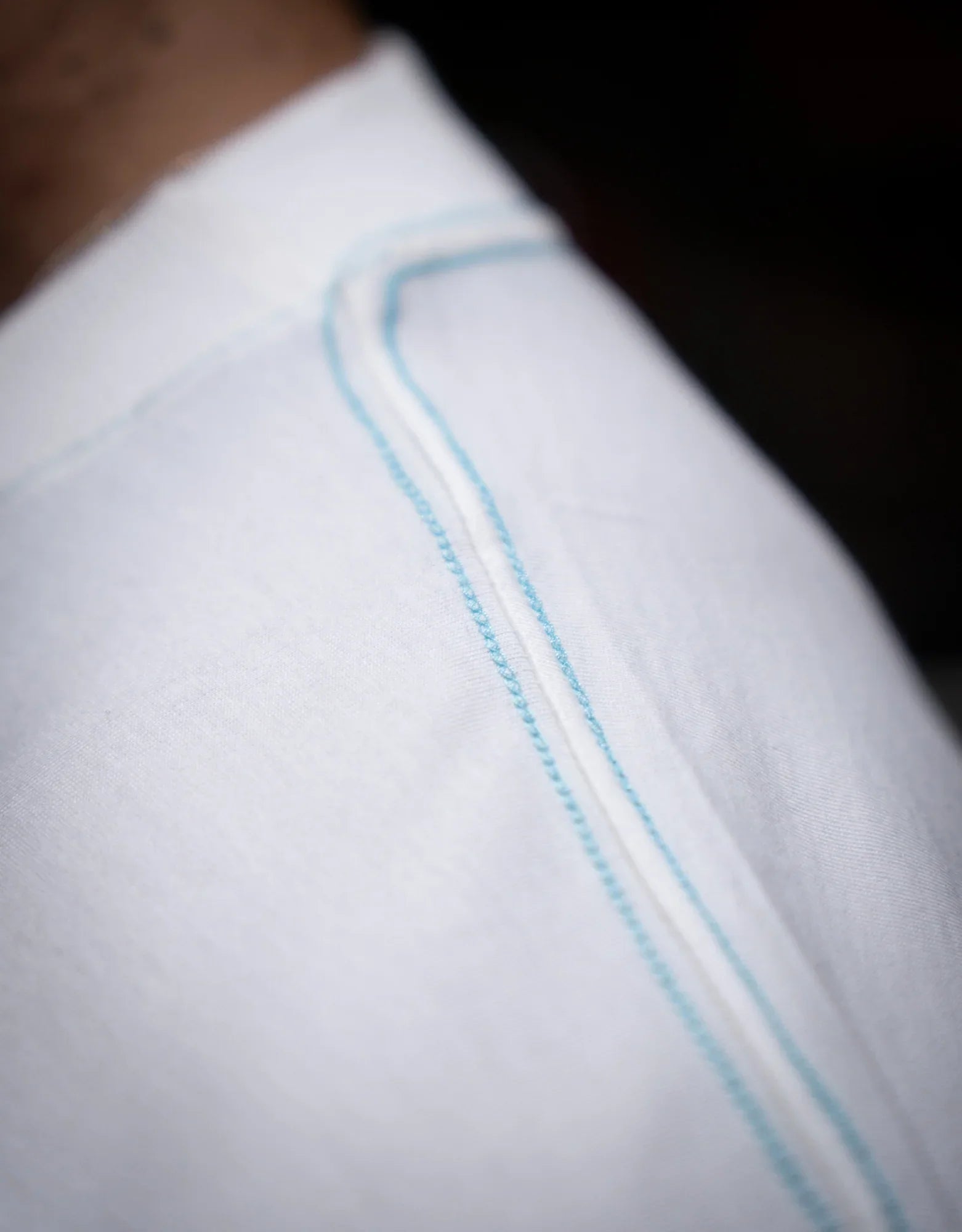 Close-up of white pants waistband with blue stitching on model