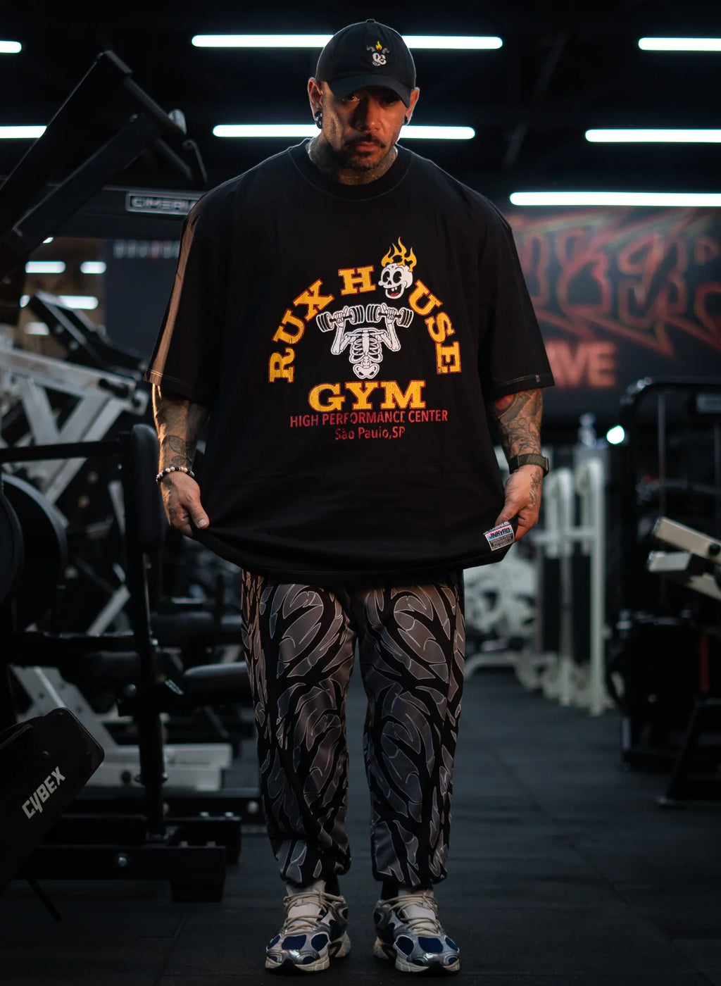 Model wearing patterned gym pants and sneakers in a gym setting
