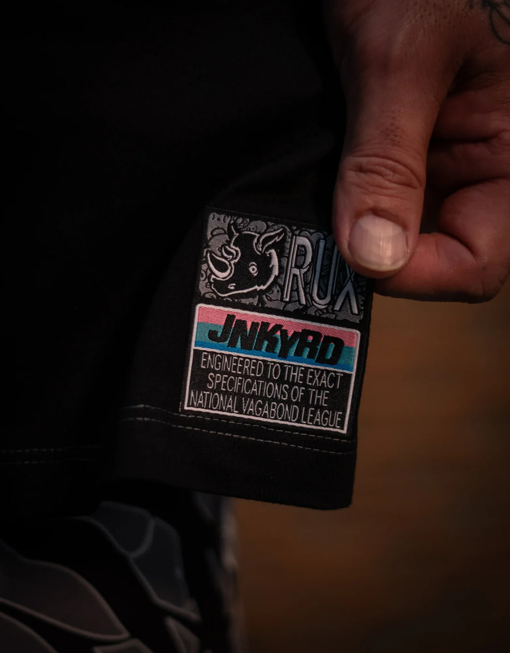 Model wearing black pants, closeup of colorful patch with rhino graphic and text details