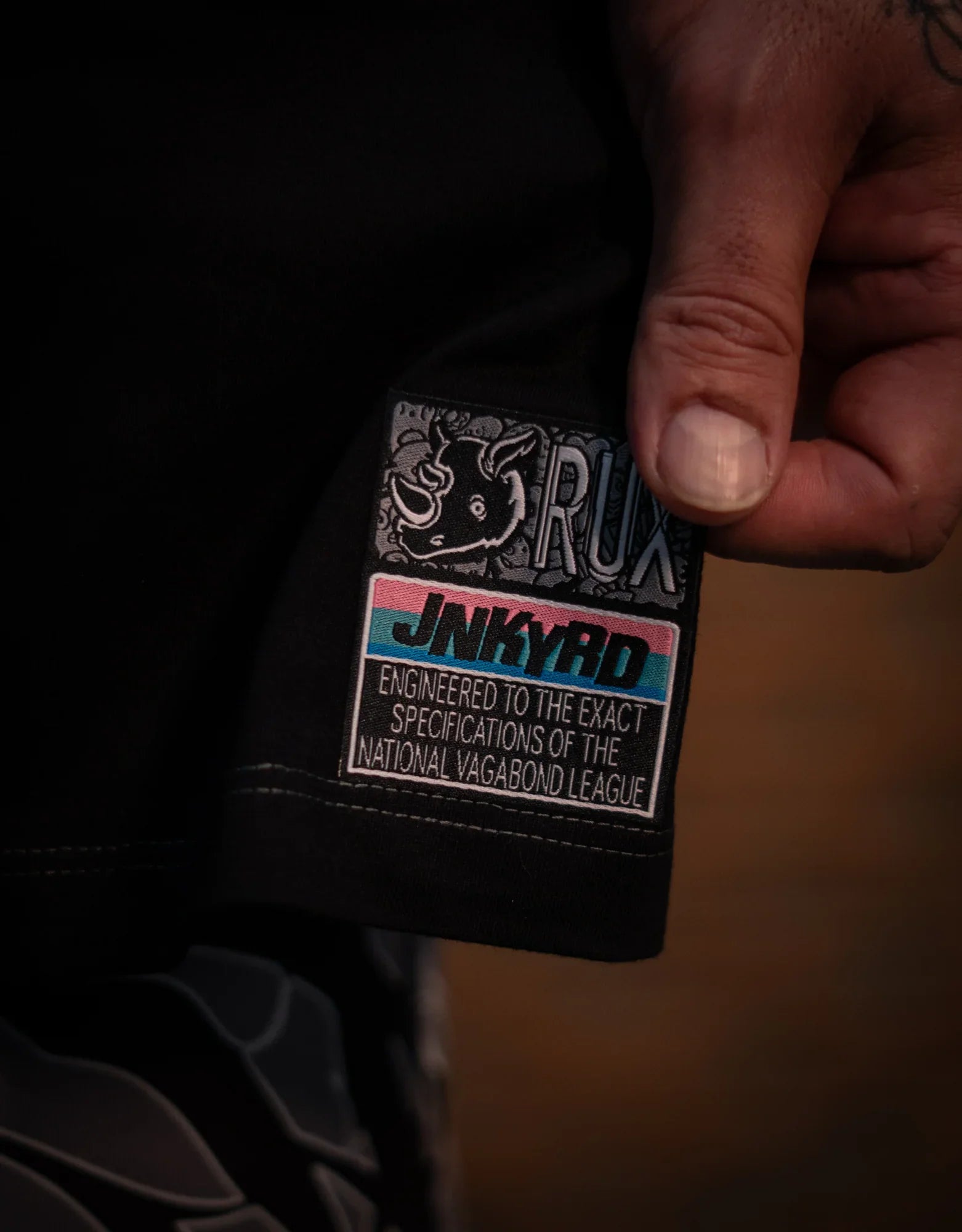Model wearing black pants, closeup of colorful patch with rhino graphic and text details