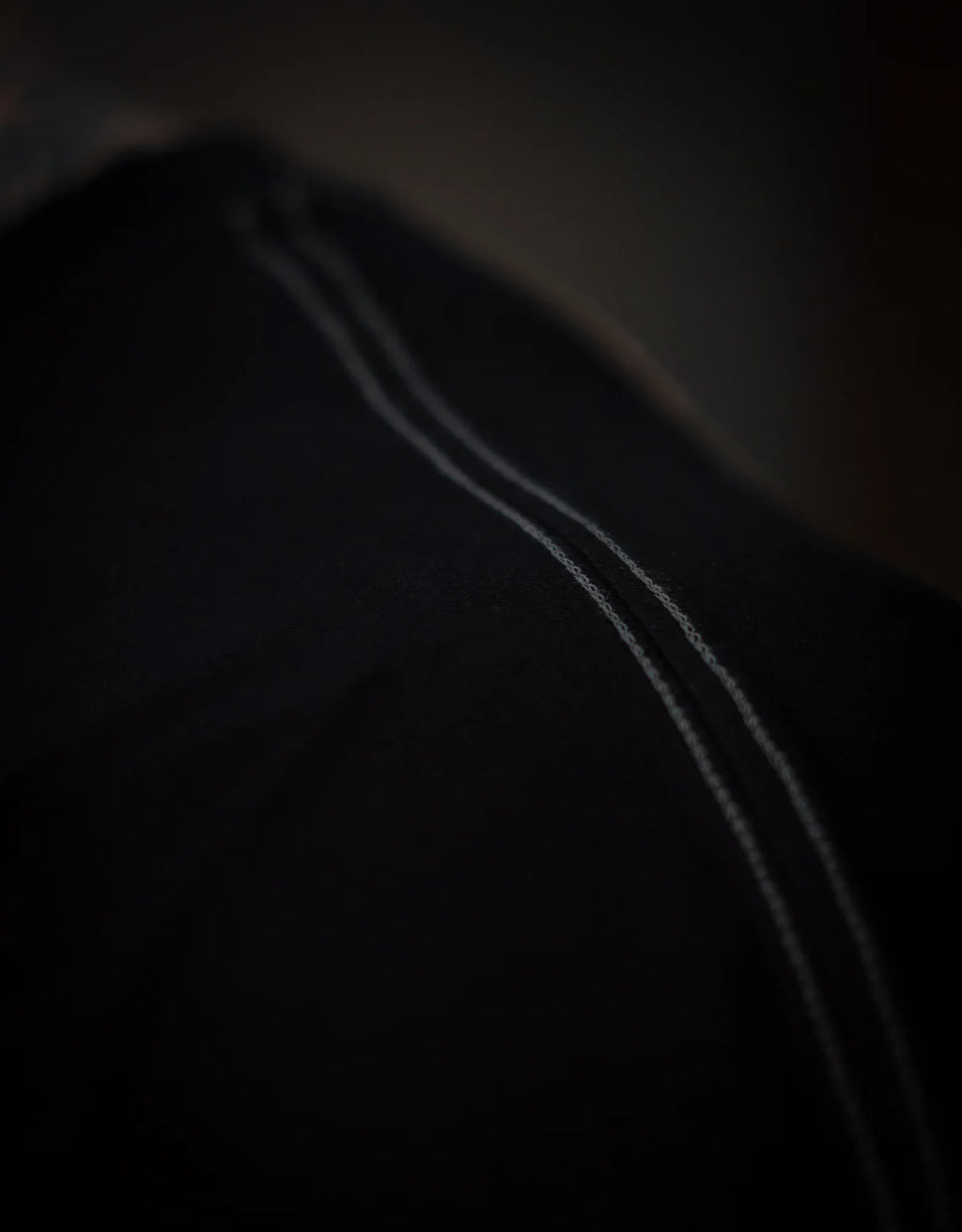 Close-up view of black pants with visible white stitching detail