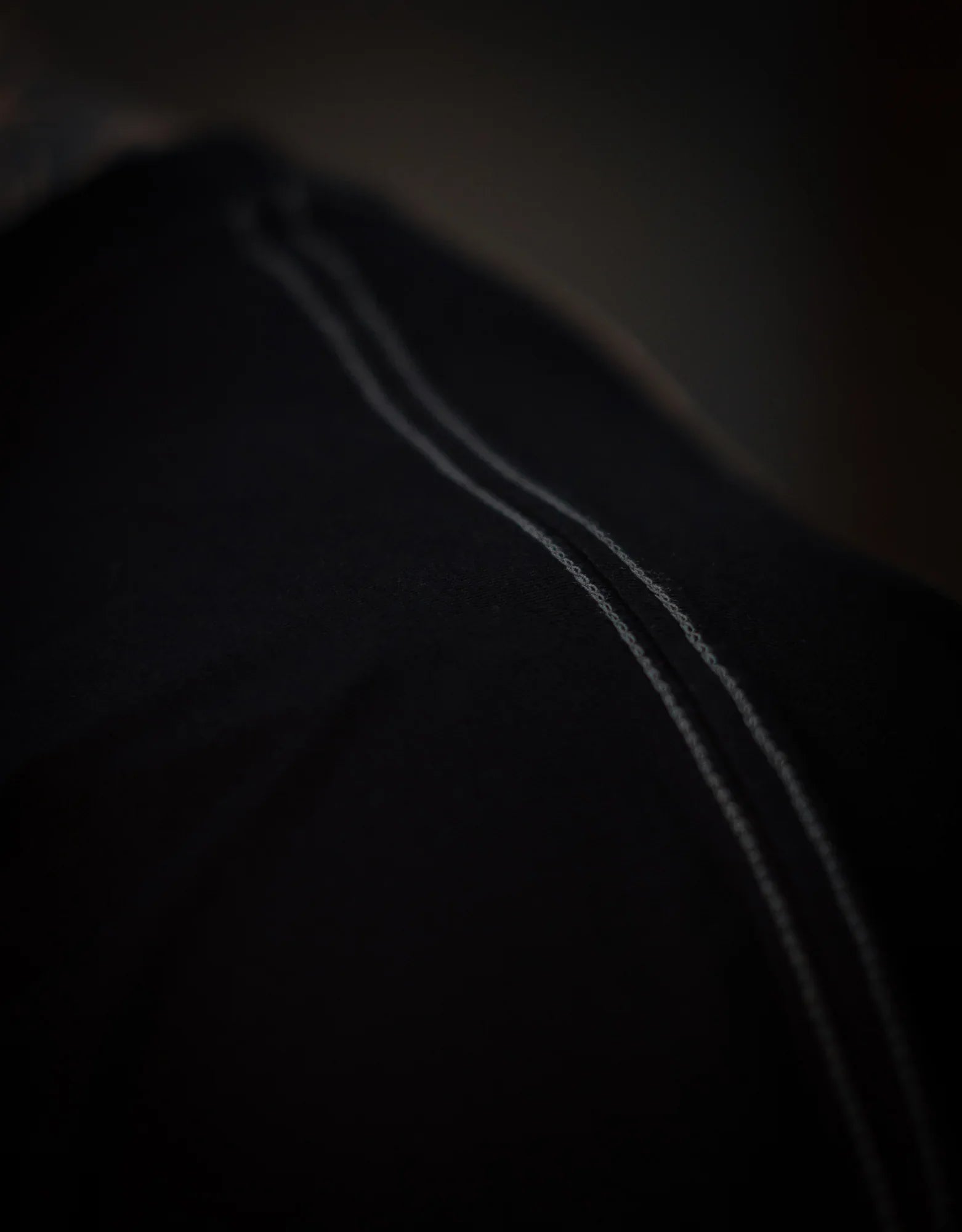 Close-up view of black pants with visible white stitching detail