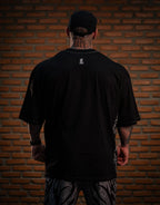 Model wearing black graphic pants, shown from behind, with a black oversized shirt