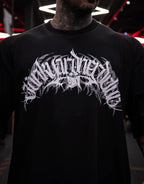 Model wearing black graphic t-shirt with bold white design, indoor setting