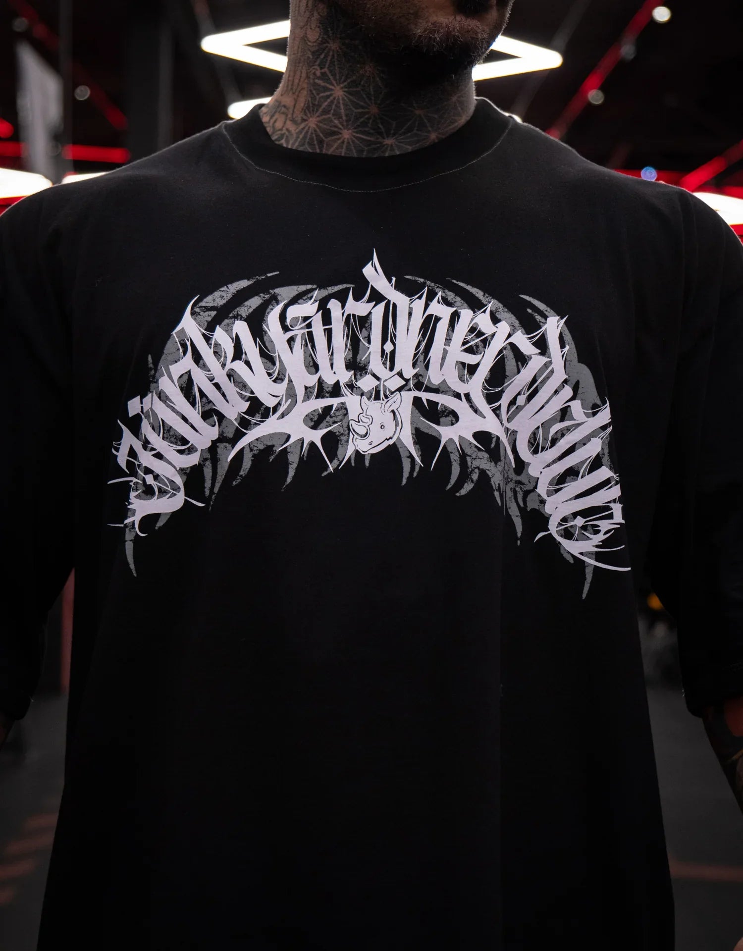 Model wearing black graphic t-shirt with bold white design, indoor setting