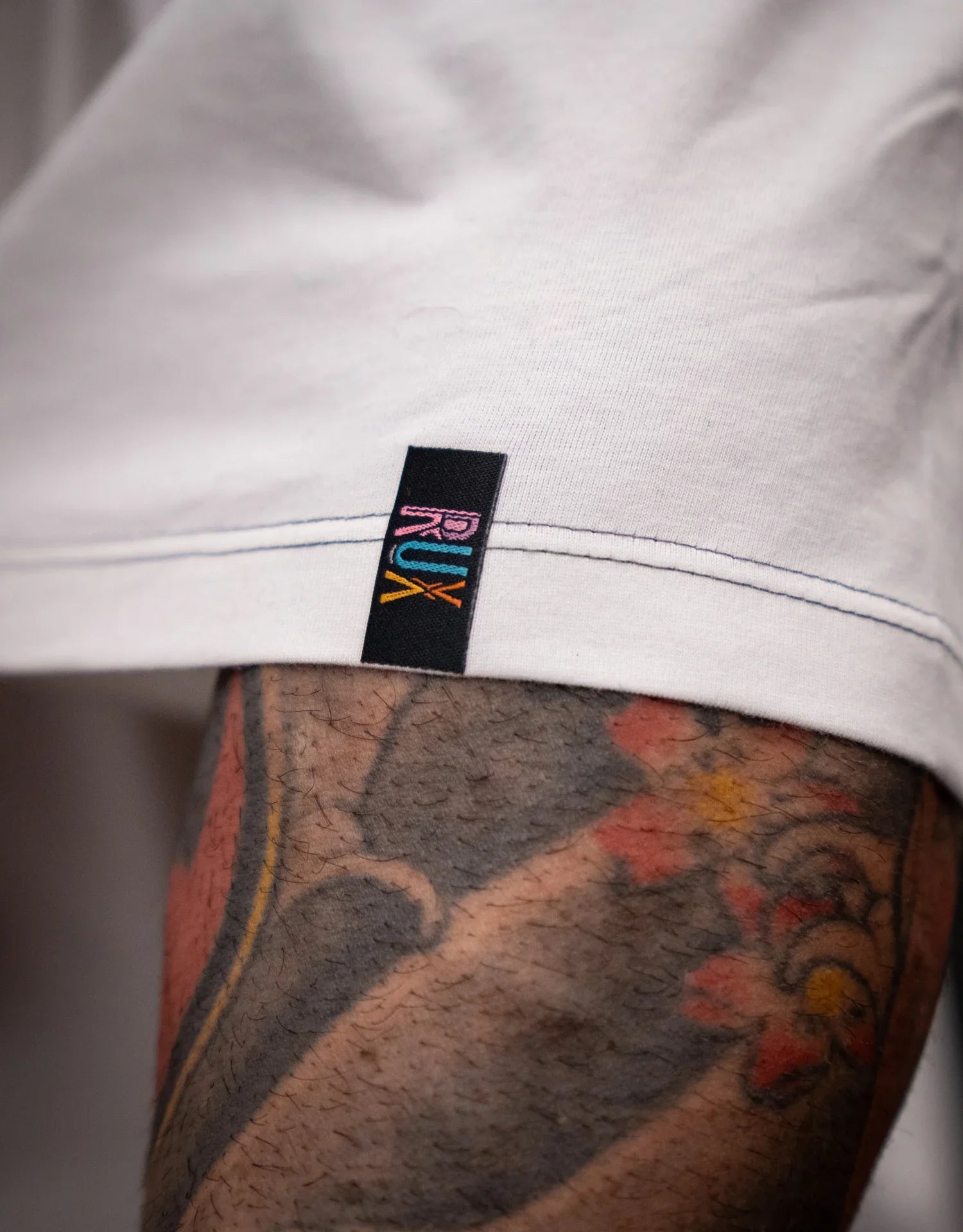 Model wearing off-white pants with visible tag and leg tattoo detail