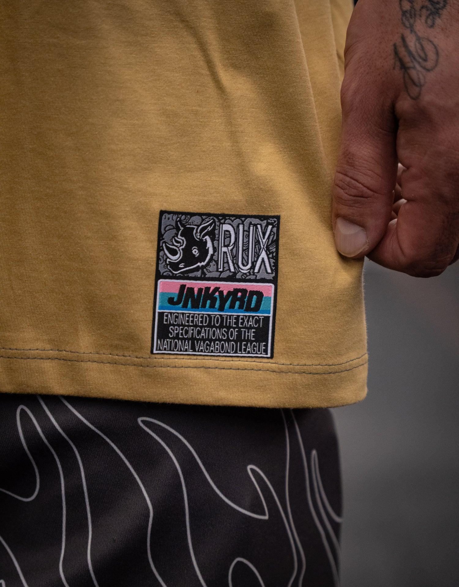 Model wearing patterned black pants, close-up of graphic yellow shirt and hand tattoo