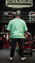Model wearing patterned gym pants in a fitness center, viewed from behind