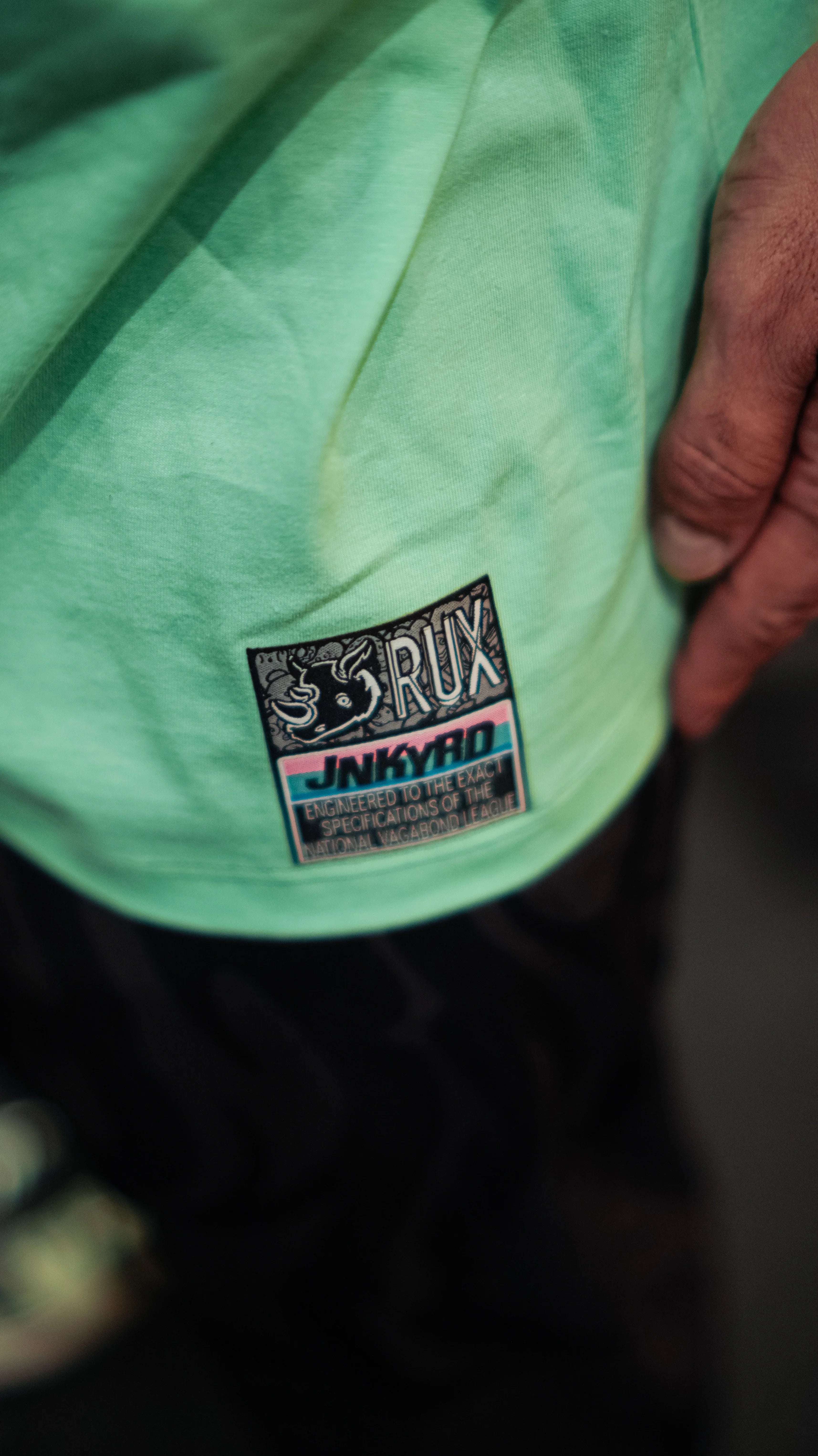 Model wearing the pants with a visible green shirt tag and hand resting on the side