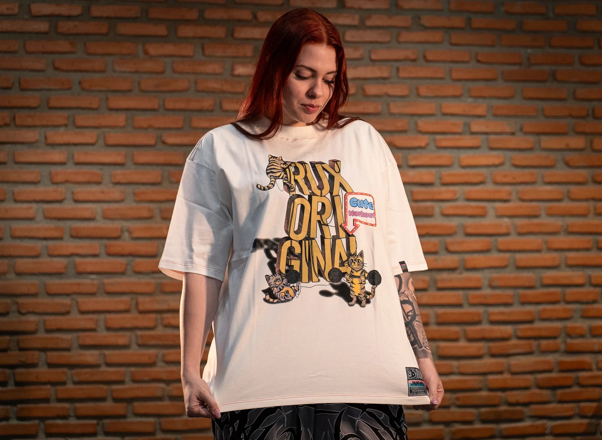 Model wearing patterned black pants and an oversized graphic t-shirt with cat illustrations