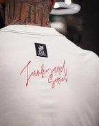 Close up of model wearing white t-shirt with 'Junkyard Series' red text and neck tattoo visible