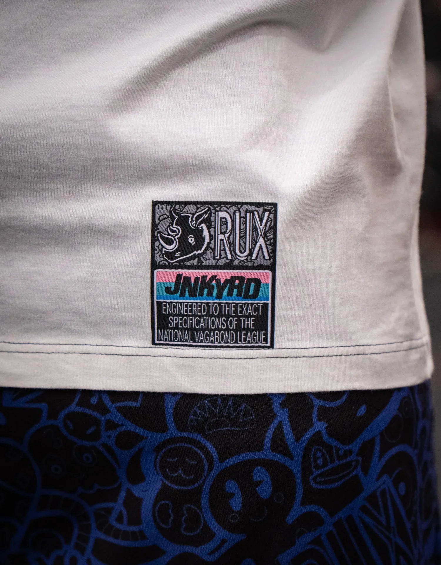 Model wearing patterned pants with blue cartoon faces and white shirt with visible label.