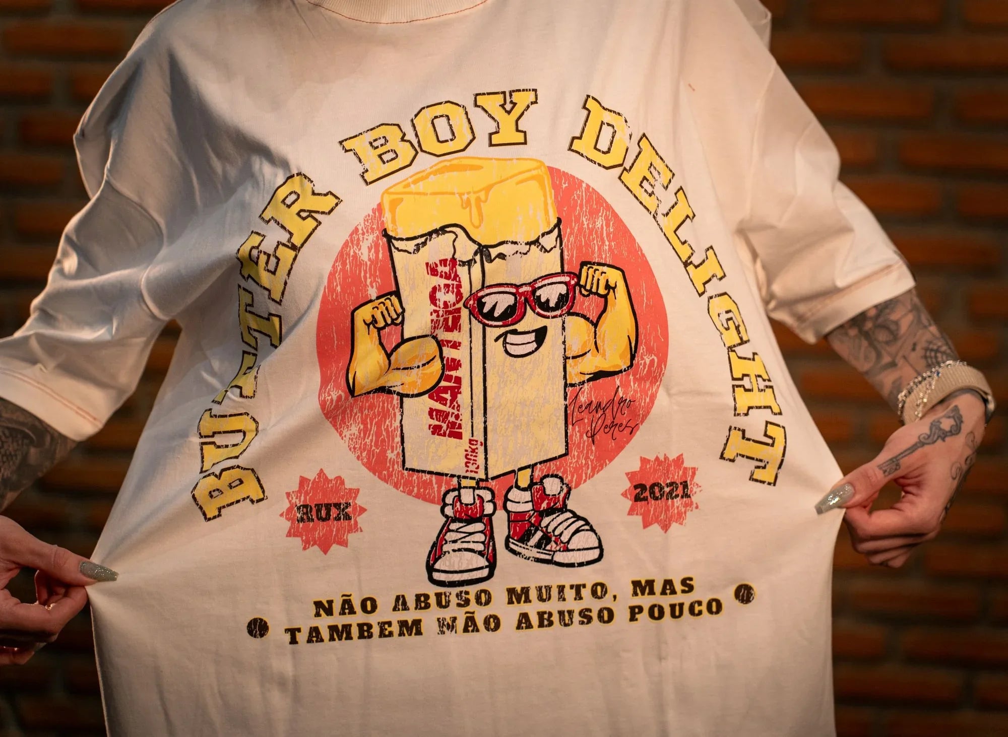 Model wearing graphic t-shirt with cartoon butter print and Portuguese text