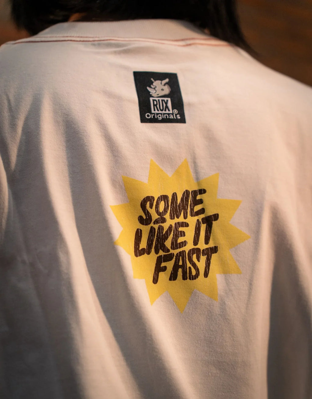 Model wearing graphic T-shirt with 'Some Like It Fast' text on back