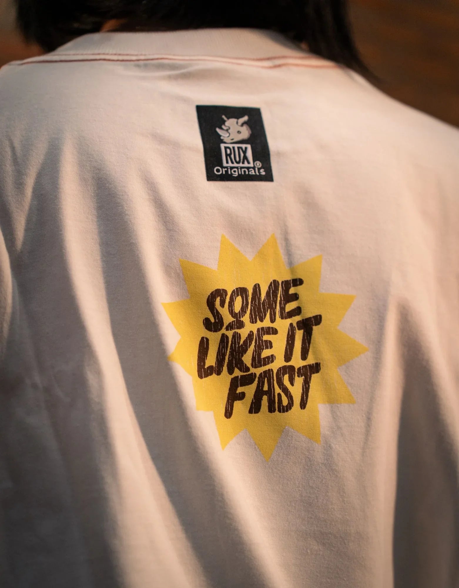 Model wearing graphic T-shirt with 'Some Like It Fast' text on back